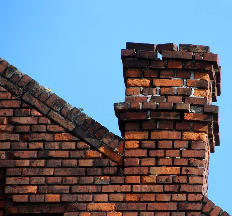 Damaged chimney on an Orland Park home showing cracks and missing mortar